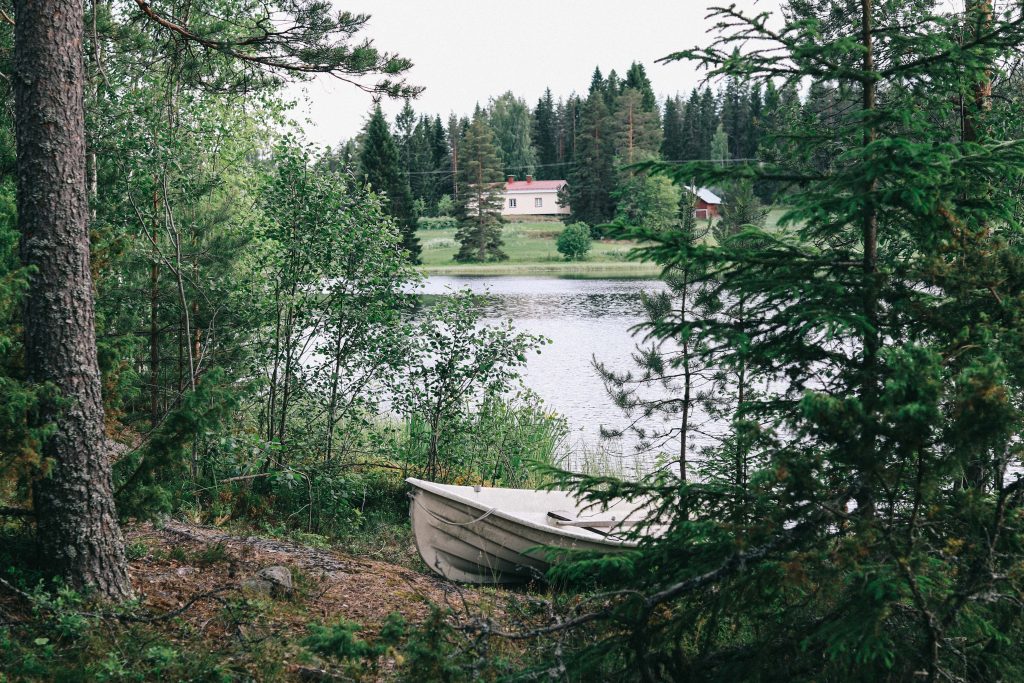 A small white boat pulled ashore one of the Finnish lakes in Tampere.