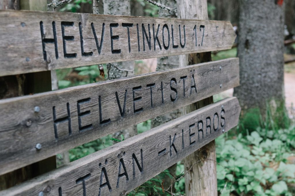 A wooden sign showing the way to Helvetinjärvi National Park.